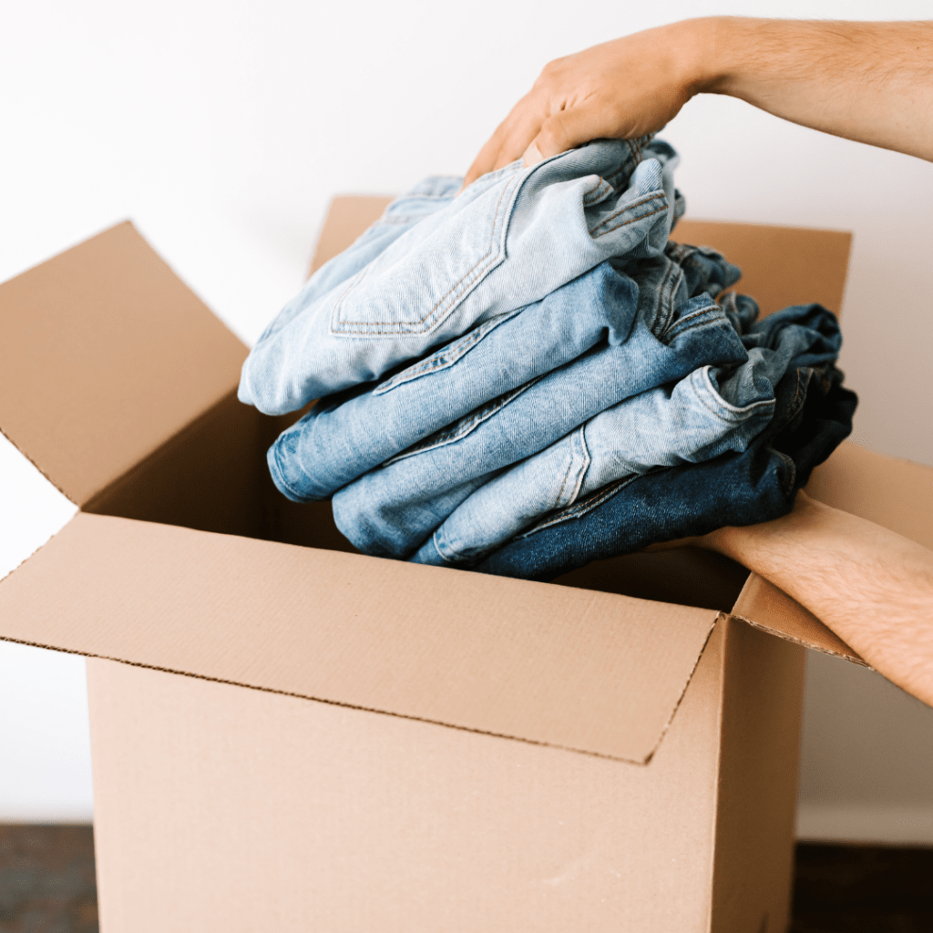 A person putting clothes in a box